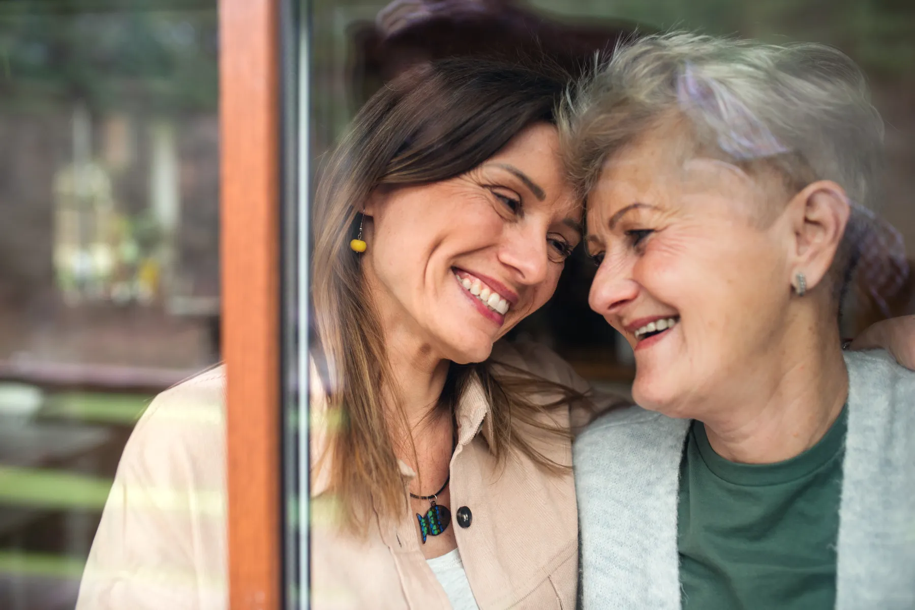 Adult daughter and senior mother smiling together